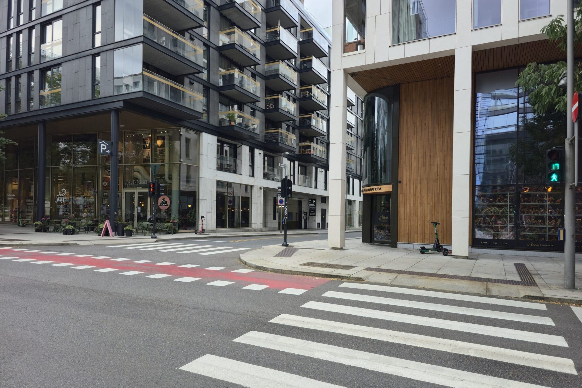 Gatehjørne i Bjørvika med butikkfasader, sykkelvei og fotgjengerfelt
