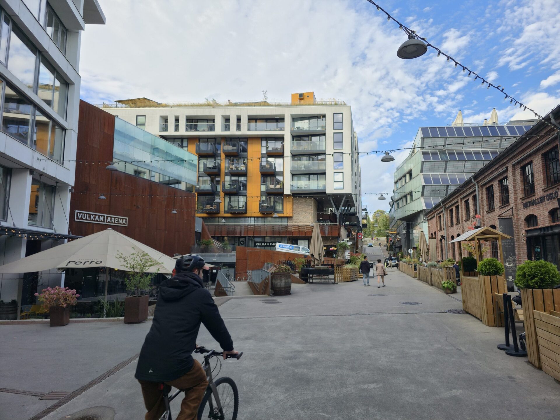 Syklist på Vulkan med uteservering og nye bygg